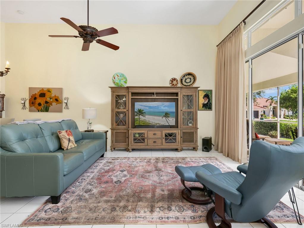 Vaulted ceiling with a ceiling fan, light-toned wall paint, tiled flooring, and sliding glass doors leading to an exterior space