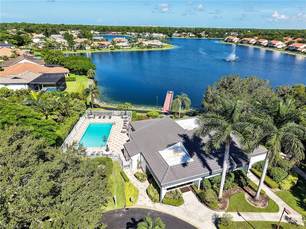 Community swimming pool with a paved deck, extensive landscaping, mature palm trees, and lakefront access