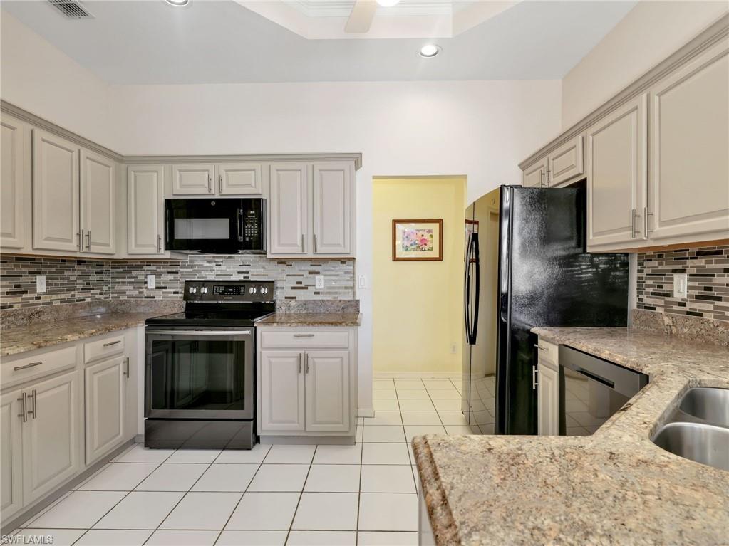 Kitchen featuring light-toned cabinetry, a mosaic tile backsplash, stone-finish countertops, and white square tile flooring