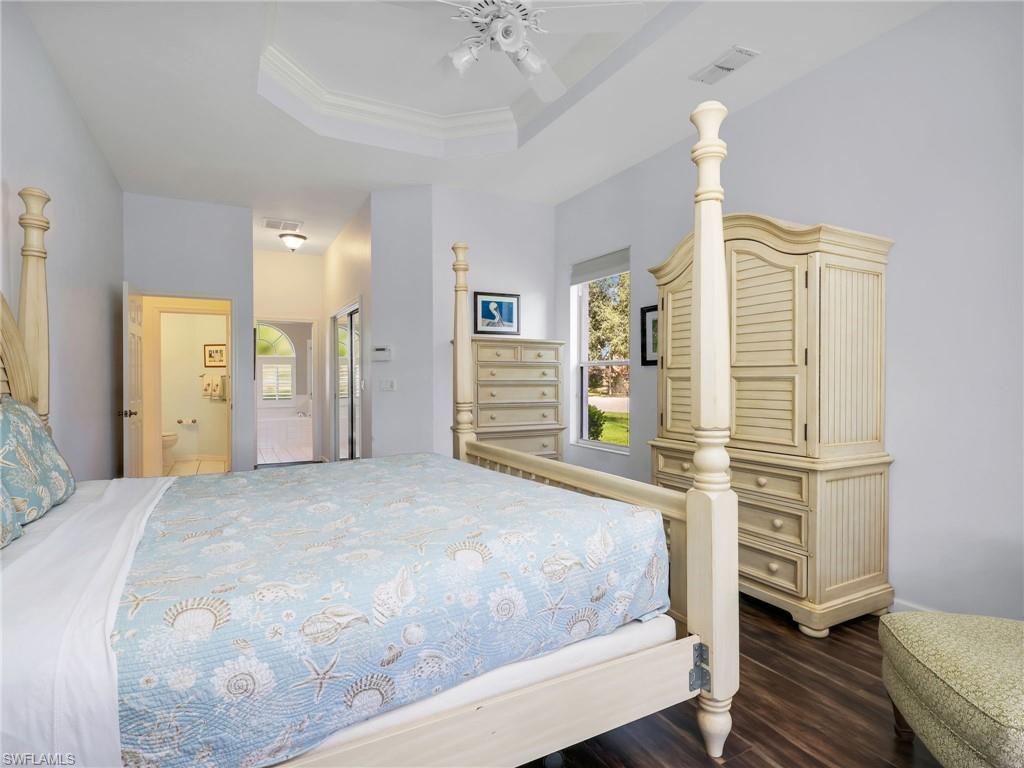 Tray ceiling, ceiling fan, wood-finish flooring, recessed lighting, and window with exterior landscaping