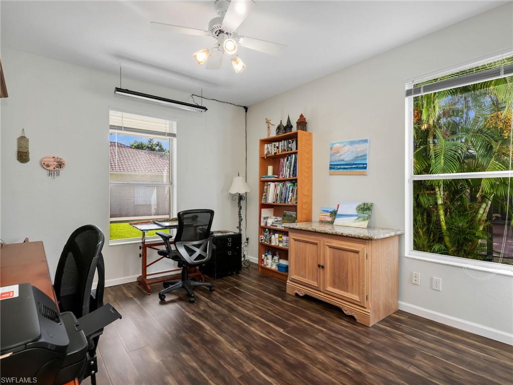 Wood-finish flooring, multiple windows, built-in cabinetry with a stone countertop, and a ceiling fan