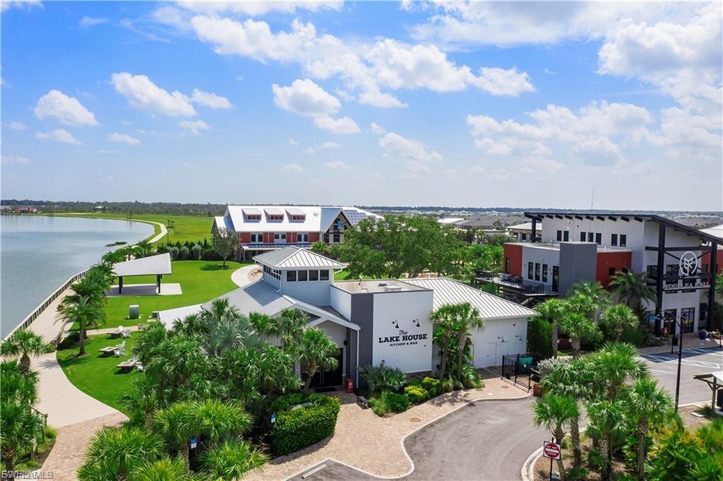 Waterfront property featuring modern mixed-use architecture with multiple buildings, expansive manicured grounds with mature palmettos and landscaped grounds, waterfront promenade with curved pathways, and panoramic water views across the property