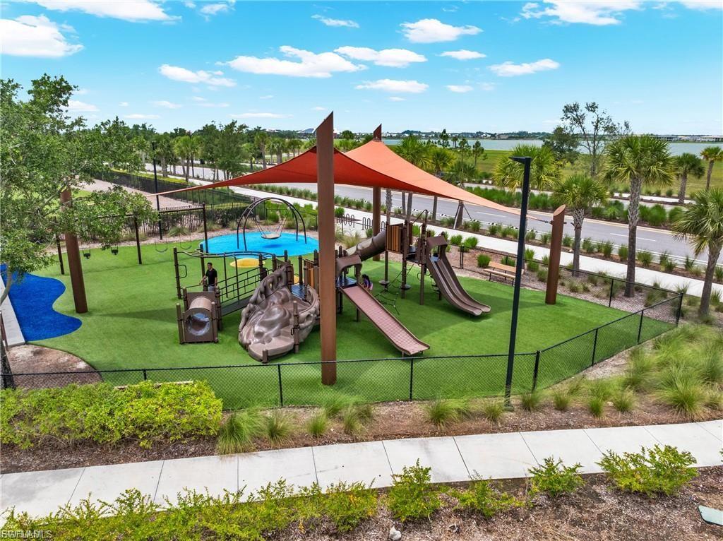 Playground with artificial turf surfacing, multiple slide structures, a swing, and a shade canopy