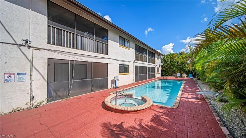Expansive outdoor living space featuring a resort-style swimming pool with integrated spa, terracotta brick decking, and mature tropical landscaping