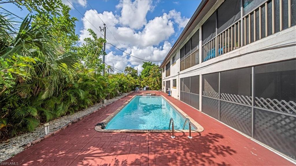 Resort-style swimming pool with crystal-clear water and integrated entry steps, surrounded by a spacious red clay deck