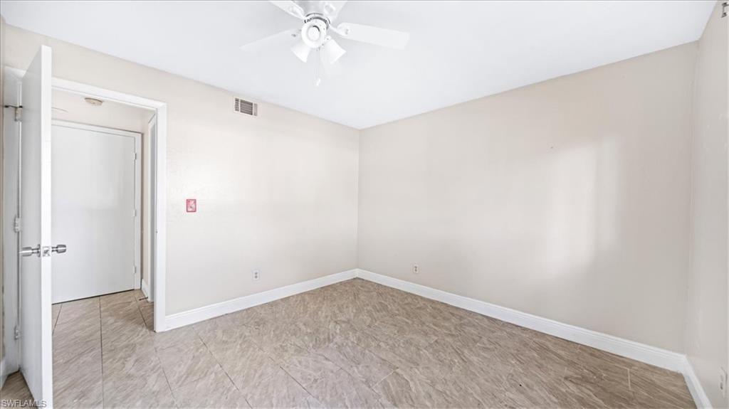 Spacious interior room featuring neutral wall finishes, wood-finish flooring, and ceiling fan with integrated lighting