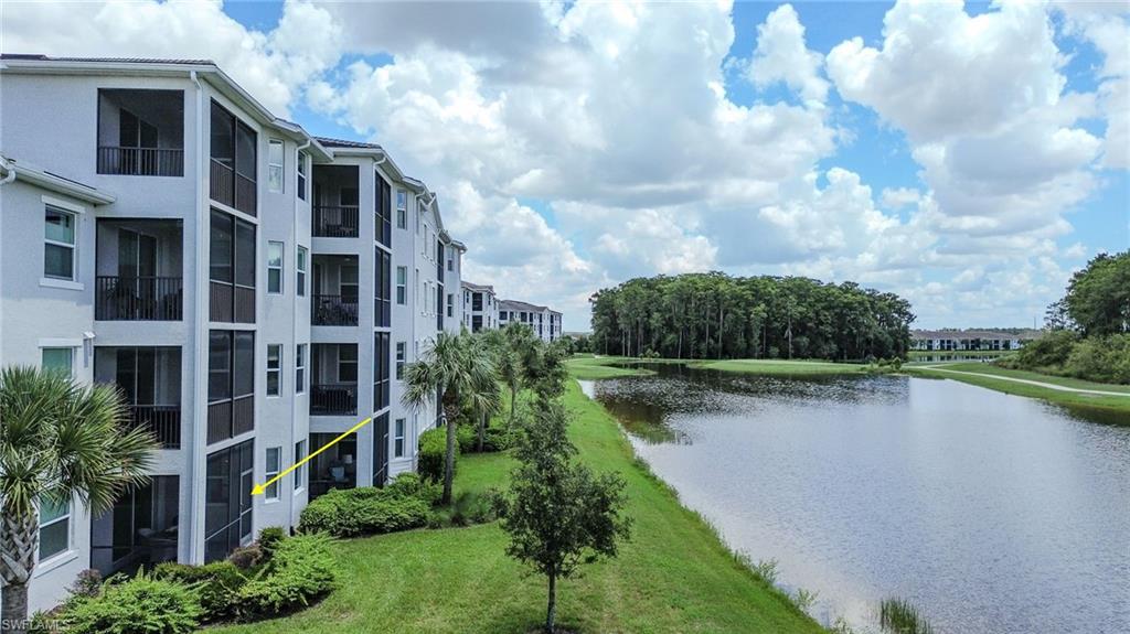 Multi-story residential building with screened lanais and balconies, featuring a waterside location with surrounding landscaping, and natural tree lines