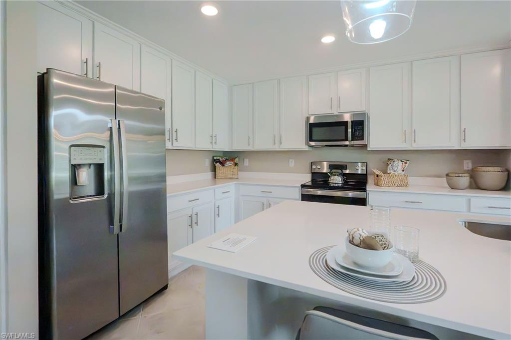 Kitchen featuring white cabinetry, light-toned countertops, stainless steel appliances, and a central island