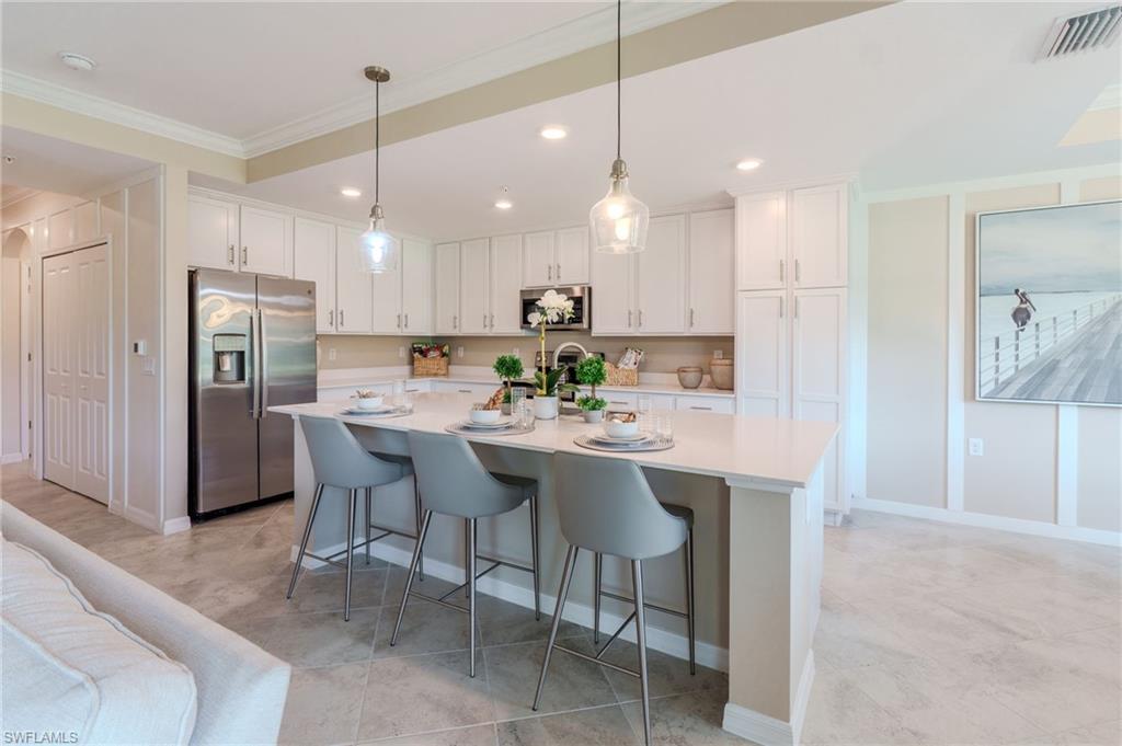 Kitchen featuring a central island, white cabinetry, integrated stainless steel appliances, and pendant lighting