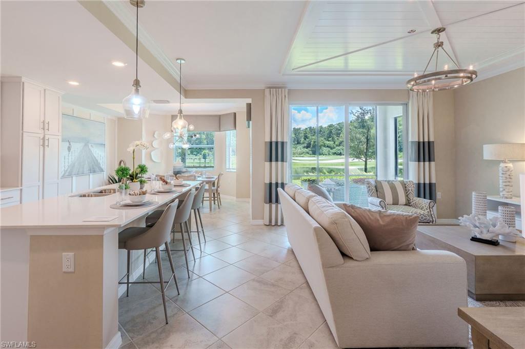 Open-concept living area with large format tile flooring and a tray ceiling