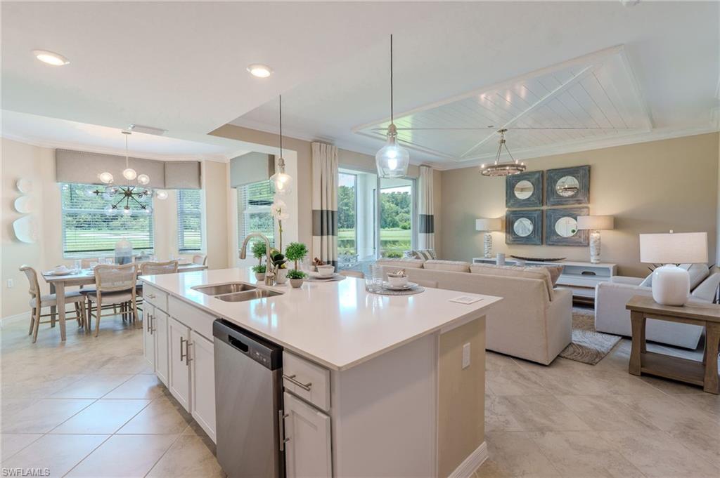 Open-concept interior featuring a kitchen island with sink, stainless steel dishwasher, bay window dining area, and a living area with a coffered ceiling