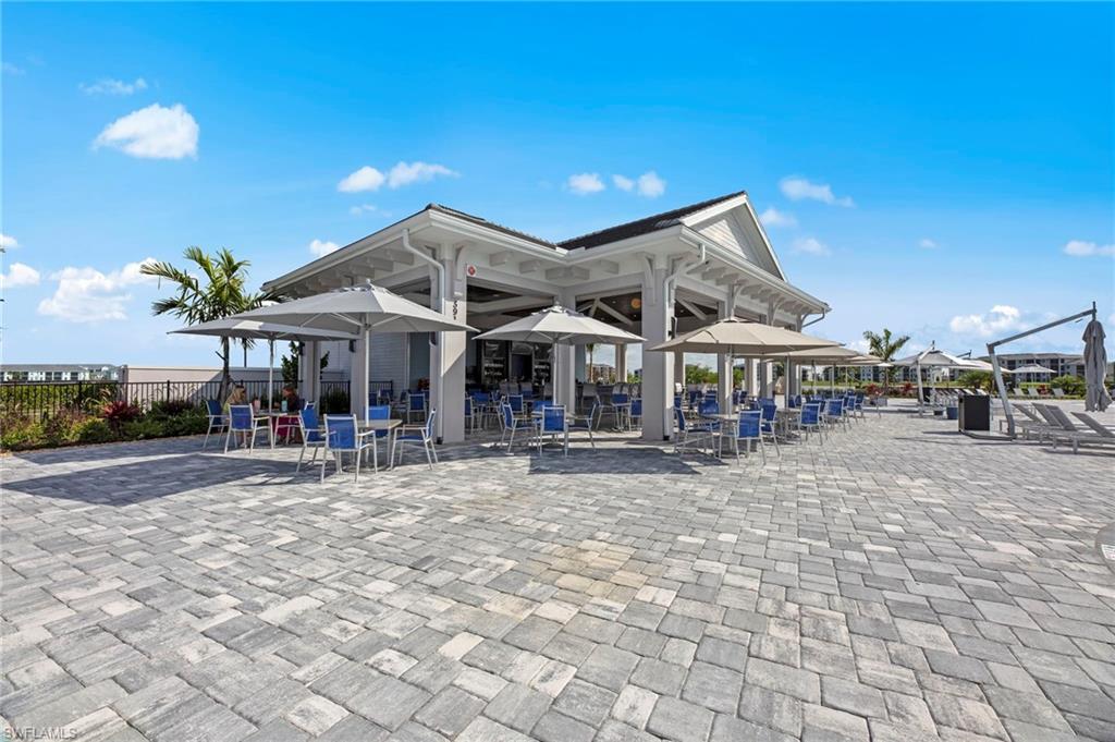 Paver patio with a white-finished structure, dark roof, and multiple seating areas with umbrellas