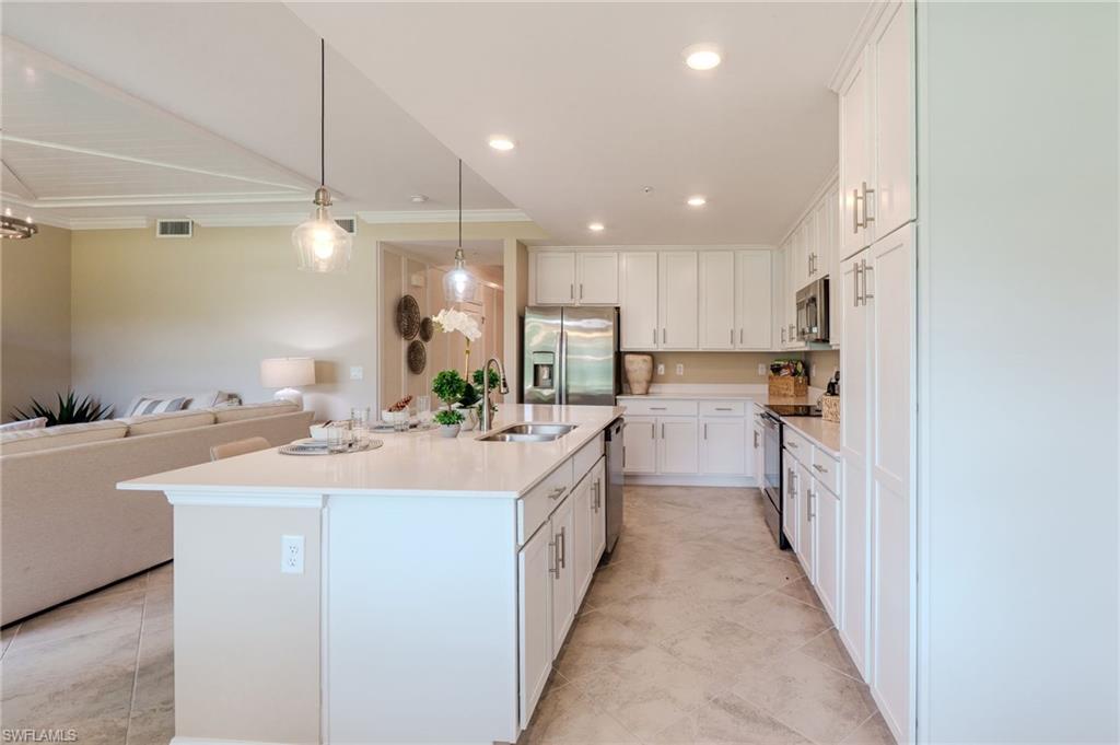 Kitchen featuring white shaker cabinetry, stainless steel appliances, a large center island with counter seating, pendant lighting, and recessed ceiling lights