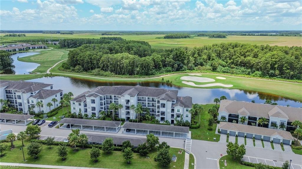 Residential buildings with multiple stories, covered parking structures, golf course, water feature, and extensive green spaces
