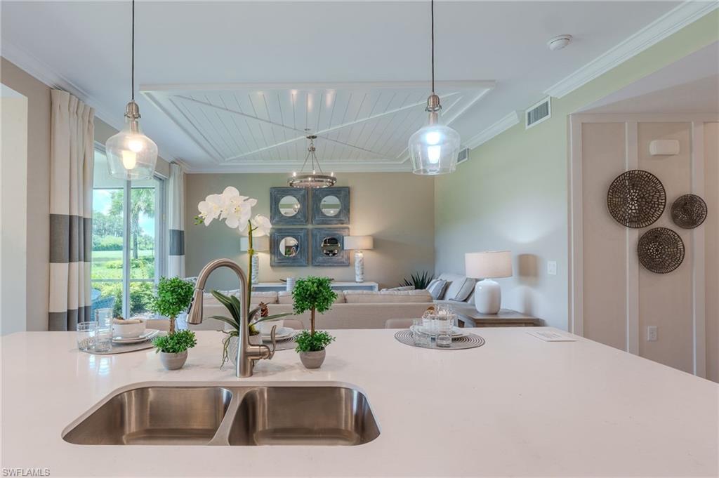 Kitchen island with a double basin stainless steel sink, gooseneck faucet, and light-toned countertop