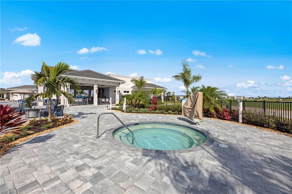 Paved patio with an in-ground spa, surrounded by lush landscaping and a covered outdoor lounge area