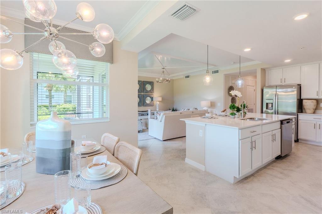Open-concept living space featuring a kitchen island with sink, stainless steel appliances, recessed lighting, and crown molding