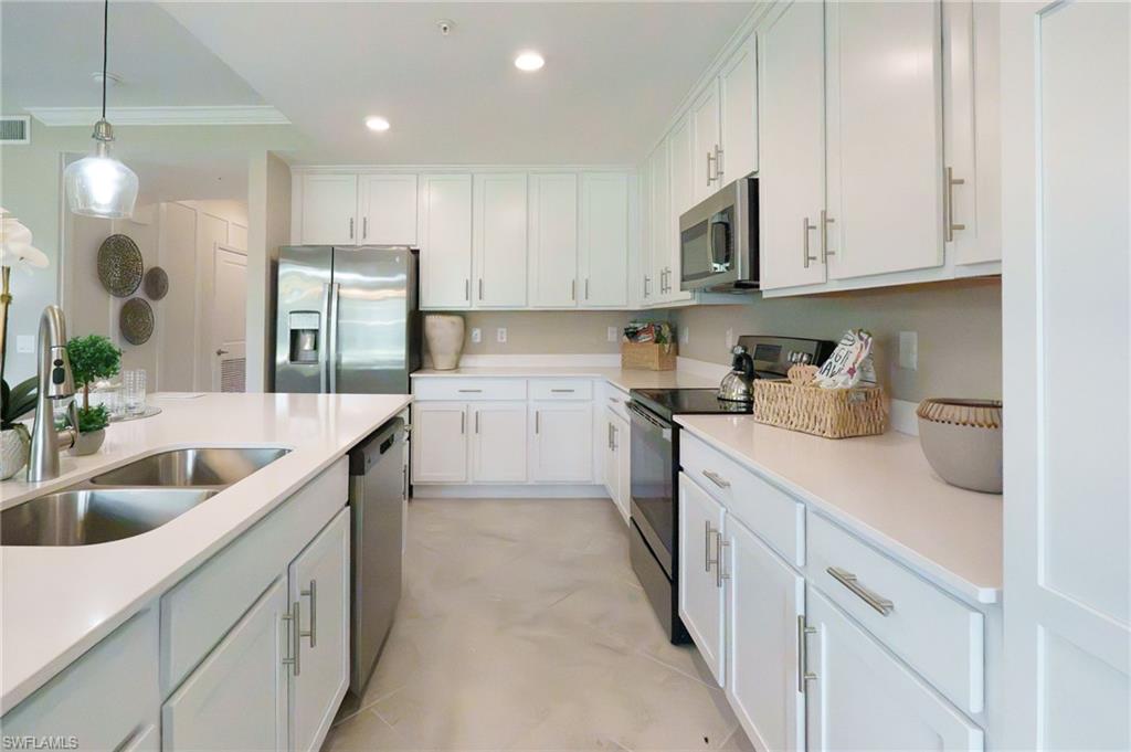 White cabinetry, stainless steel appliances, dual basin sink, integrated island, and recessed lighting
