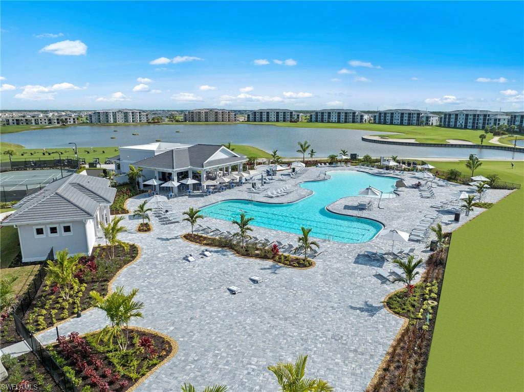 Expansive outdoor pool area with patterned paver decking, surrounding water features, and manicured landscaping