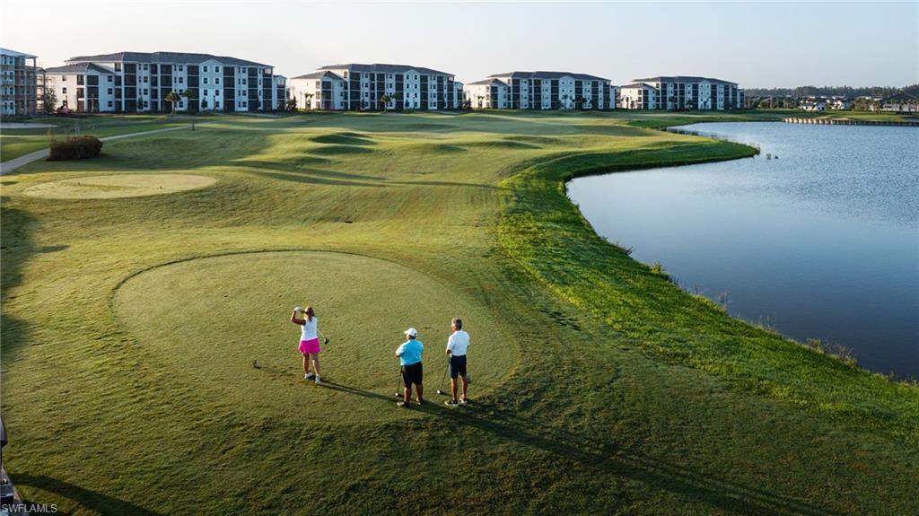 Manicured golf course featuring a tee box, expansive greens, and a water feature