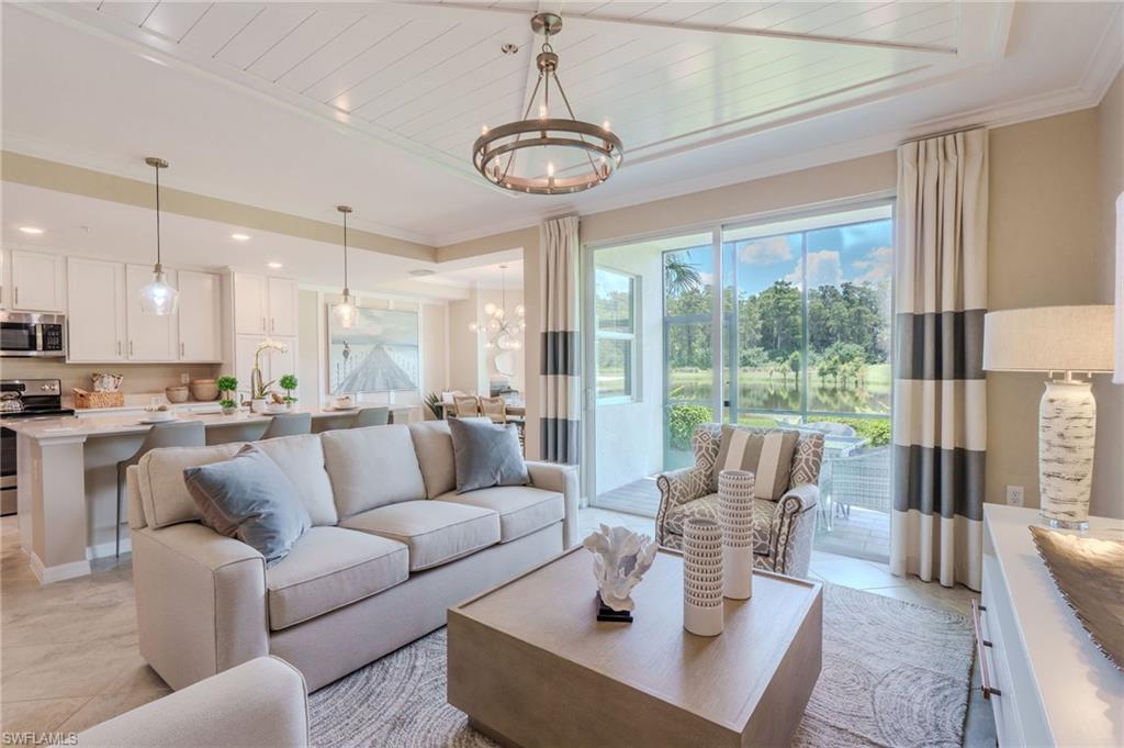 Open-concept living space featuring a tray ceiling with wood-finish planks, recessed lighting, and a contemporary chandelier