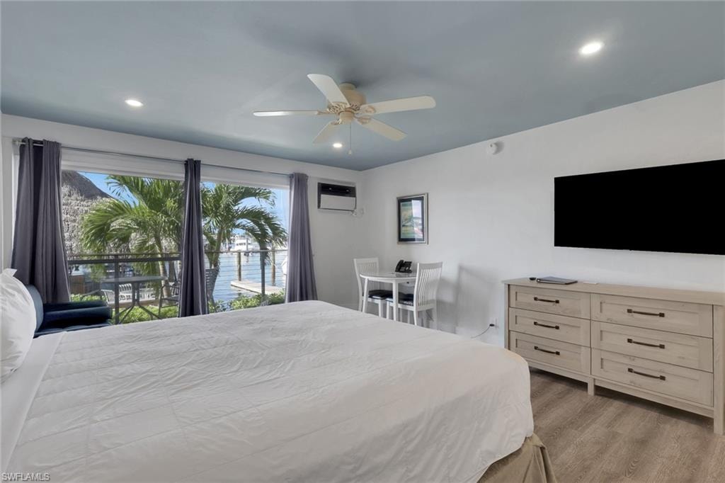 Expansive window offering water frontage, wood-finish flooring, recessed lighting, and a ceiling fan