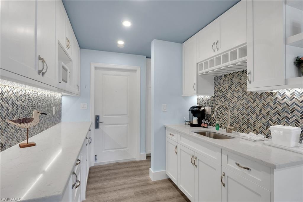 White shaker cabinetry with polished nickel hardware, quartz countertops, and a herringbone mosaic tile backsplash