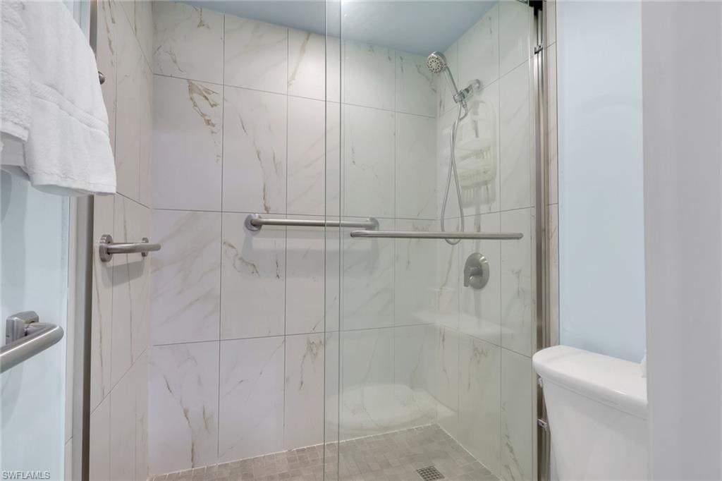 Shower with glass enclosure, white tile walls, a built-in shower bench, and a textured tile floor
