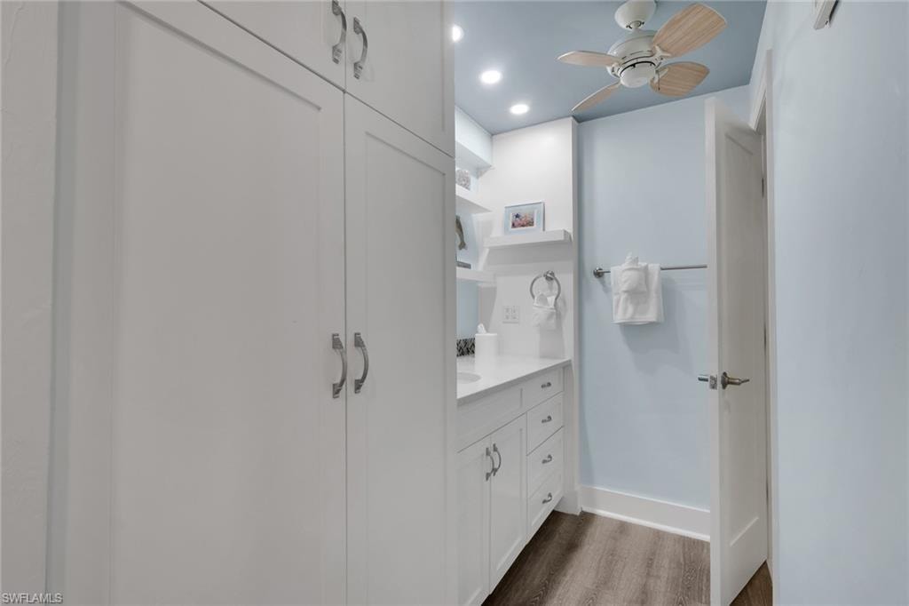 Integrated white cabinetry, wood-finish flooring, recessed lighting, and a ceiling fan