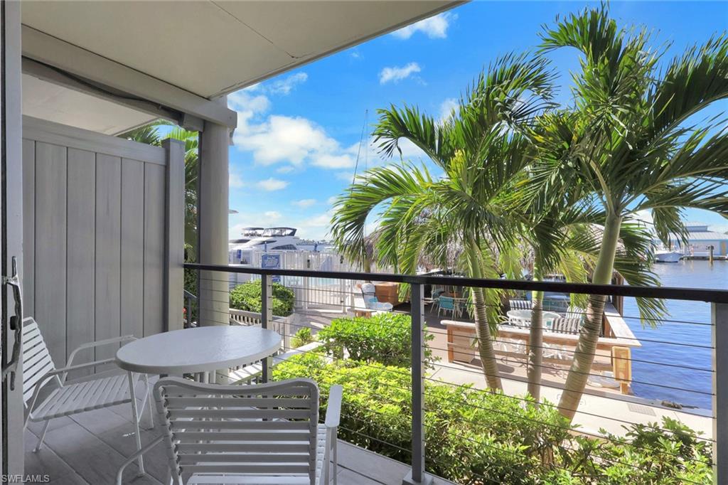 Balcony with cable railing, water frontage, lush landscaping, and a dock