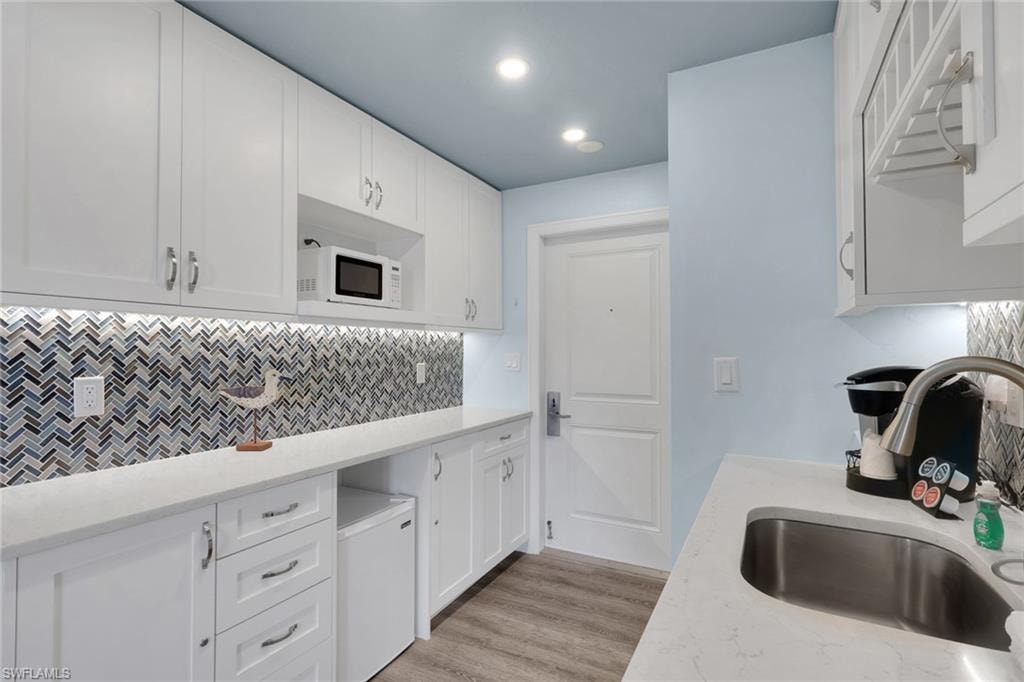 White shaker cabinetry with polished nickel hardware, quartz countertops, and a herringbone mosaic tile backsplash