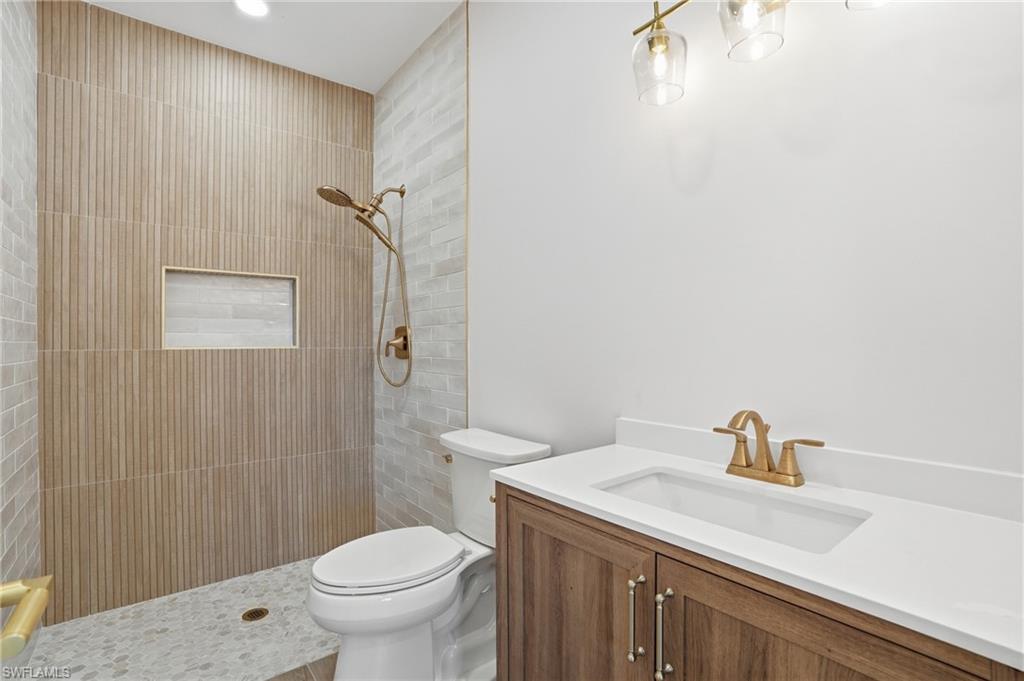 The bathroom features a walk-in shower with textured wall tiles, a recessed shower shelf, and a gold-toned shower fixture - Virtually Edited Image
