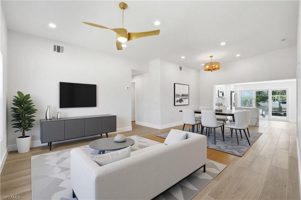 VIRTUALLY STAGEDBright and open living area featuring light-colored flooring, recessed lighting, and a vaulted ceiling with a modern ceiling fan - Virtually Edited Image