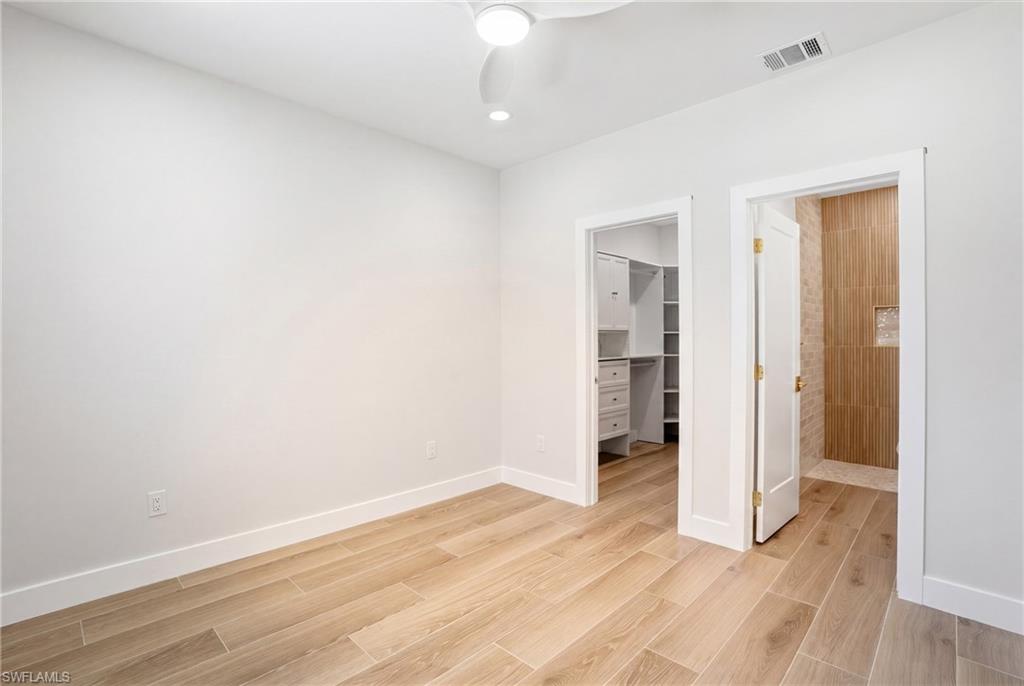 The room features light-colored wood flooring, white walls, and a ceiling fan with integrated lighting - Virtually Edited Image