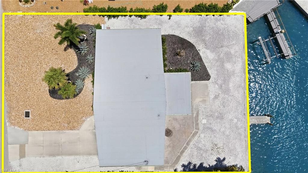 Aerial view showcasing the property's waterfront location, private dock, and landscaped yard with decorative gravel and plantings - Virtually Edited Image