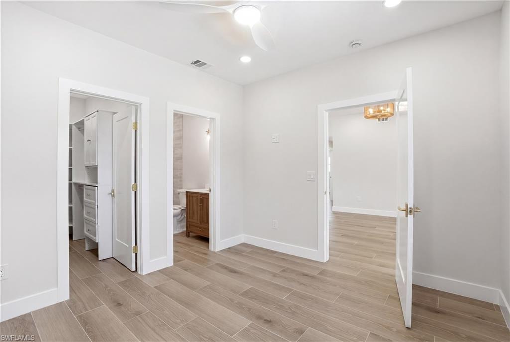 This room features light-colored tile flooring, a ceiling fan with integrated lighting, and recessed ceiling lights - Virtually Edited Image