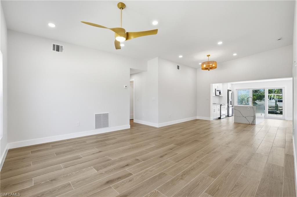 Spacious interior featuring a contemporary ceiling fan, recessed lighting, and light-toned tile flooring - Virtually Edited Image