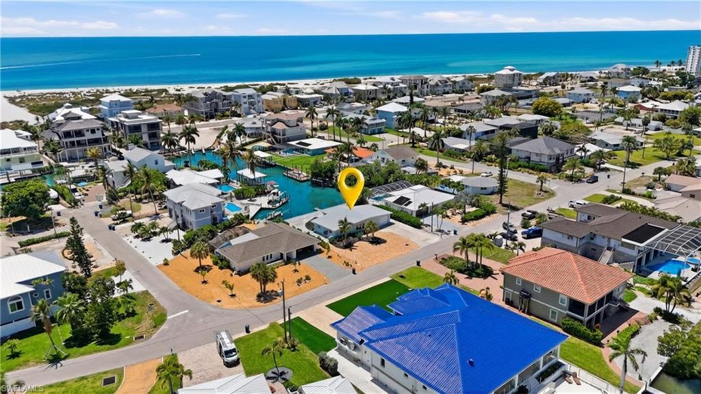 Aerial view showcasing the property's location within a coastal community, featuring nearby waterways and proximity to the beach with ocean views - Virtually Edited Image