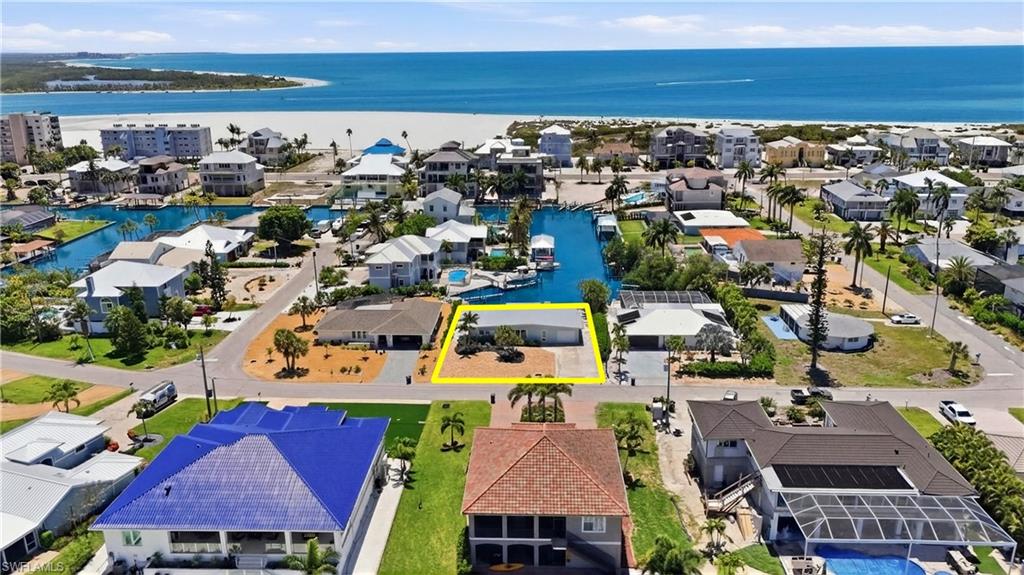 Aerial view of the property, showcasing its location near canals and a large body of water, with a beach visible in the distance - Virtually Edited Image