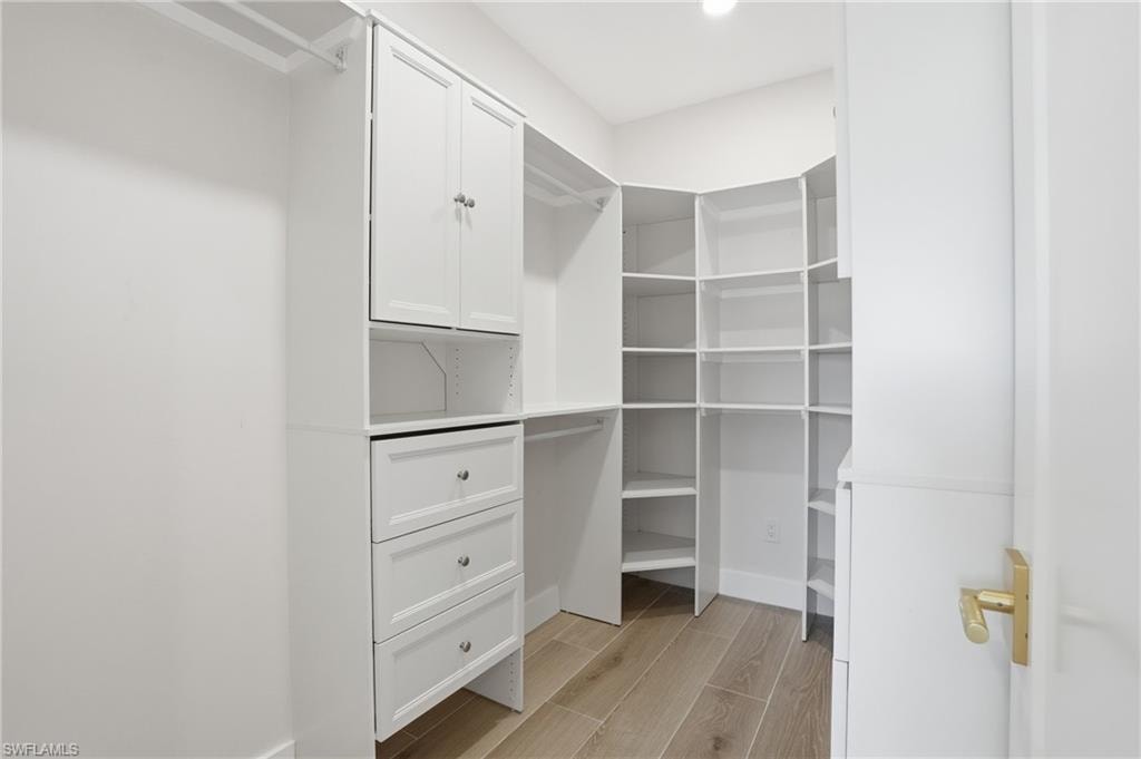 Custom closet featuring white cabinetry, drawers with silver-toned hardware, and extensive shelving - Virtually Edited Image
