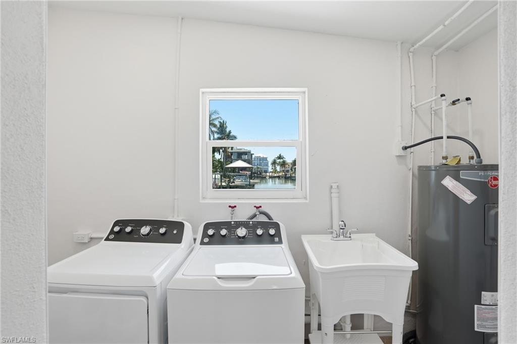 Utility room featuring a window with a water view, a laundry sink, and a water heater - Virtually Edited Image