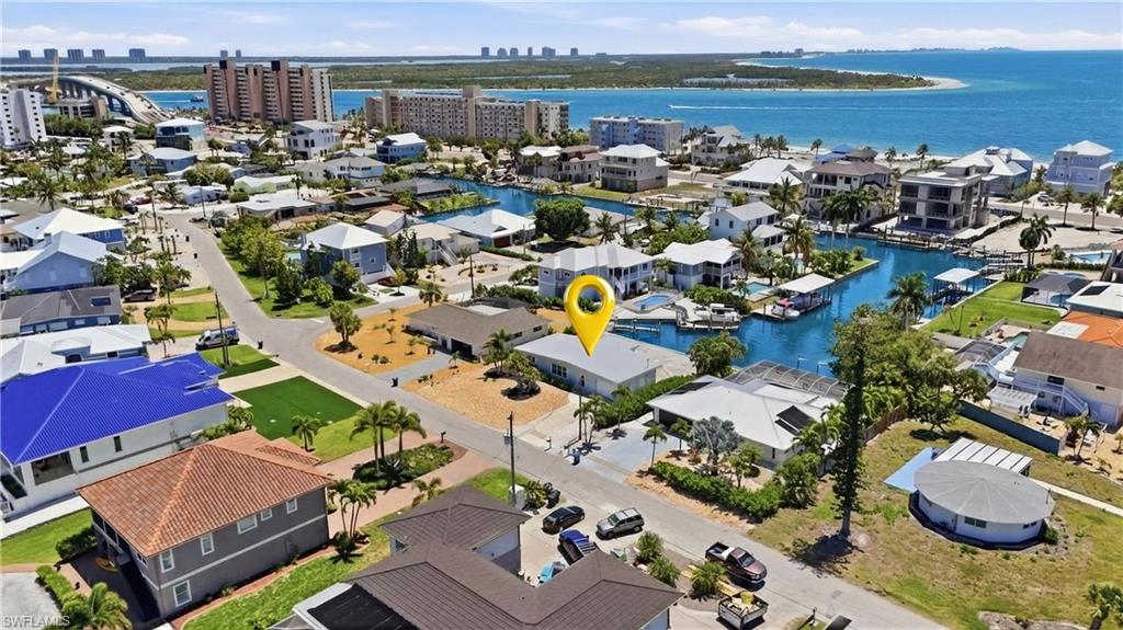 Aerial view of the property and surrounding neighborhood, featuring water views, nearby buildings, and residential streets - Virtually Edited Image