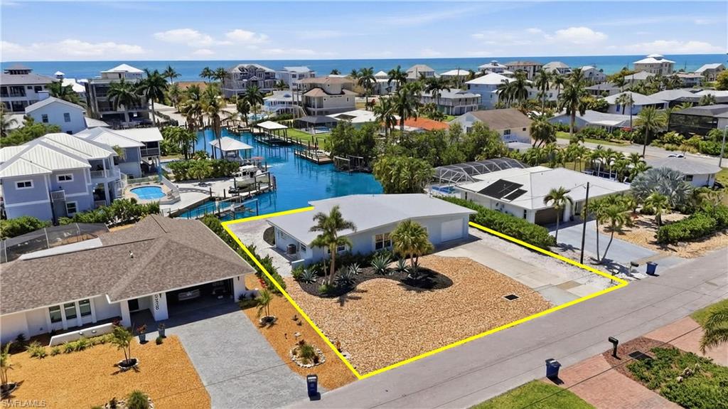 Aerial view showcasing the property's location within a coastal community, featuring nearby waterways and proximity to the beach with ocean views - Virtually Edited Image