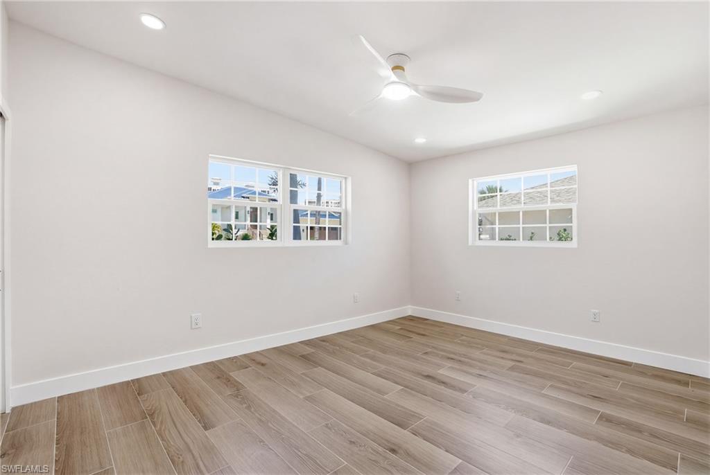 This room features wood-look tile flooring, white walls, and recessed lighting - Virtually Edited Image