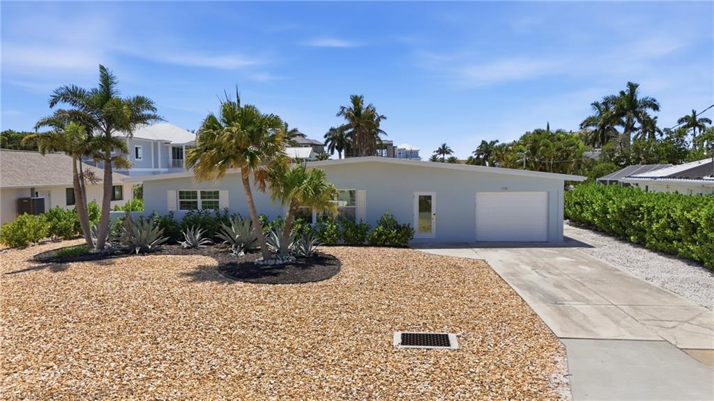 The property features a light-colored exterior, a garage with a white door, and a paved driveway - Virtually Edited Image