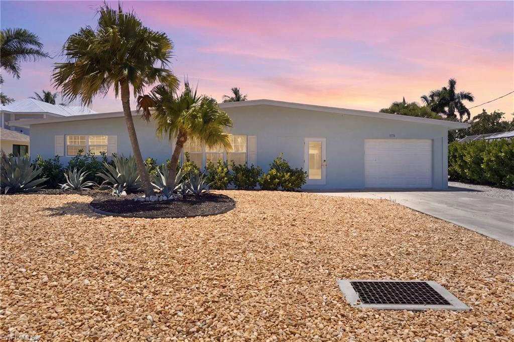 The property features a light blue exterior, a white garage door, and a well-maintained gravel yard - Virtually Edited Image