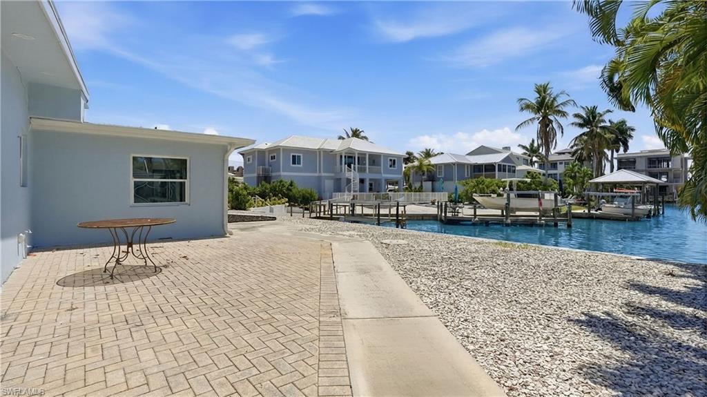 The property features a paved patio area and a waterfront setting with docks - Virtually Edited Image