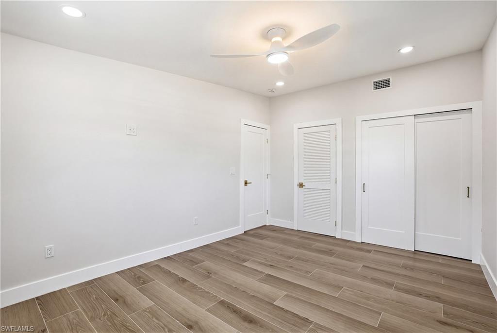 This room features wood-look tile flooring, bright white walls, and recessed lighting - Virtually Edited Image