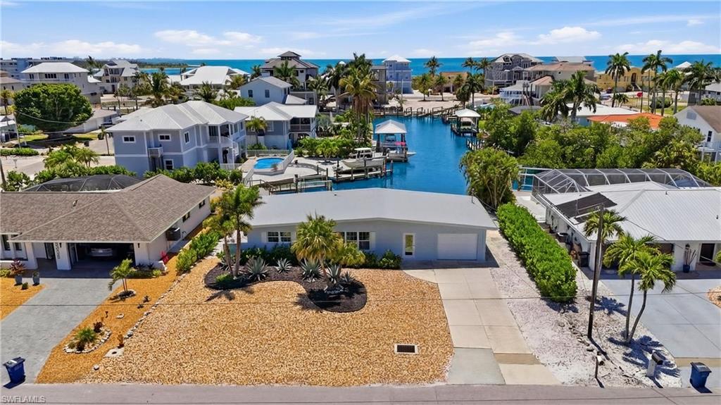 This property features a single-story residence with a garage and a well-maintained front yard with desert landscaping and tropical plants - Virtually Edited Image