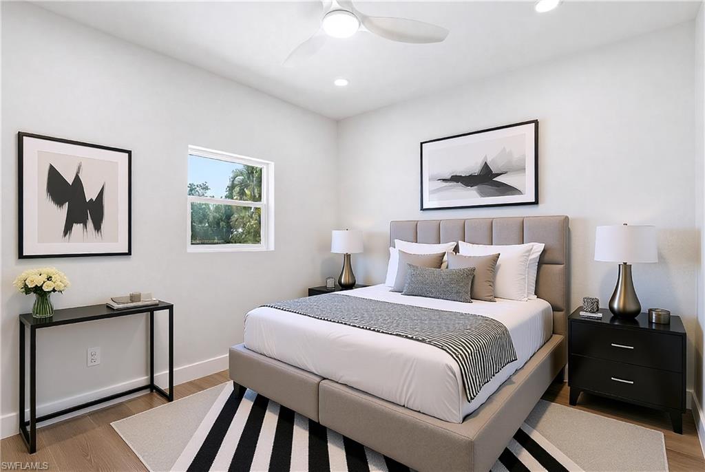 VIRTUALLY STAGED The bedroom features light wood flooring, a window providing views of greenery, and a ceiling fan with integrated lighting - Virtually Edited Image